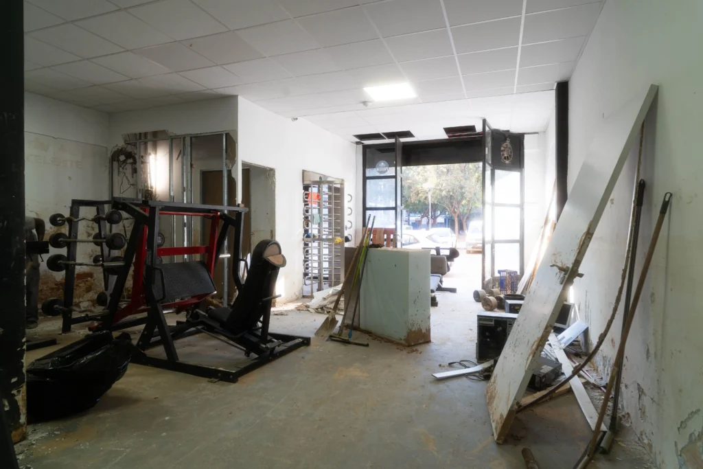 Interior del gimnasio Titán Fitness tras la inundación de la DANA, con equipos y suelo gravemente dañados.