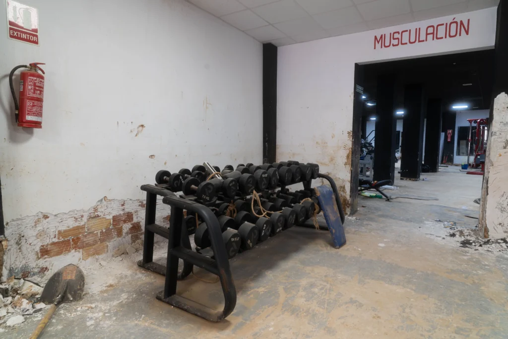 Trabajadores y miembros del equipo removiendo escombros y limpiando el gimnasio durante los primeros días de reconstrucción.